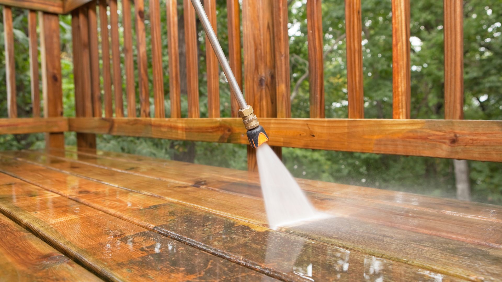 Power washer cleaning wooden deck with high-pressure water spray