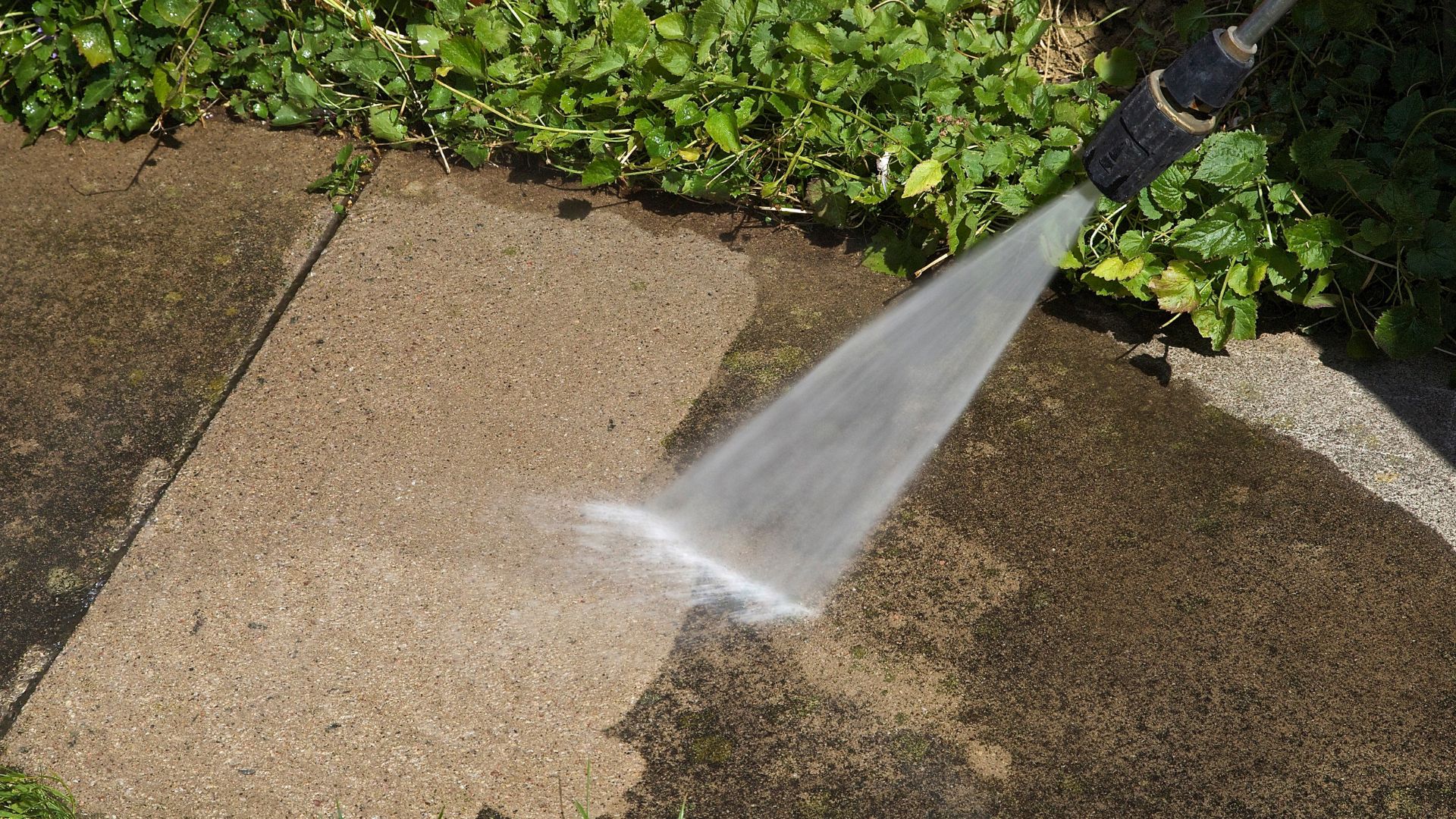 Pressure washer cleaning concrete patio with powerful water spray